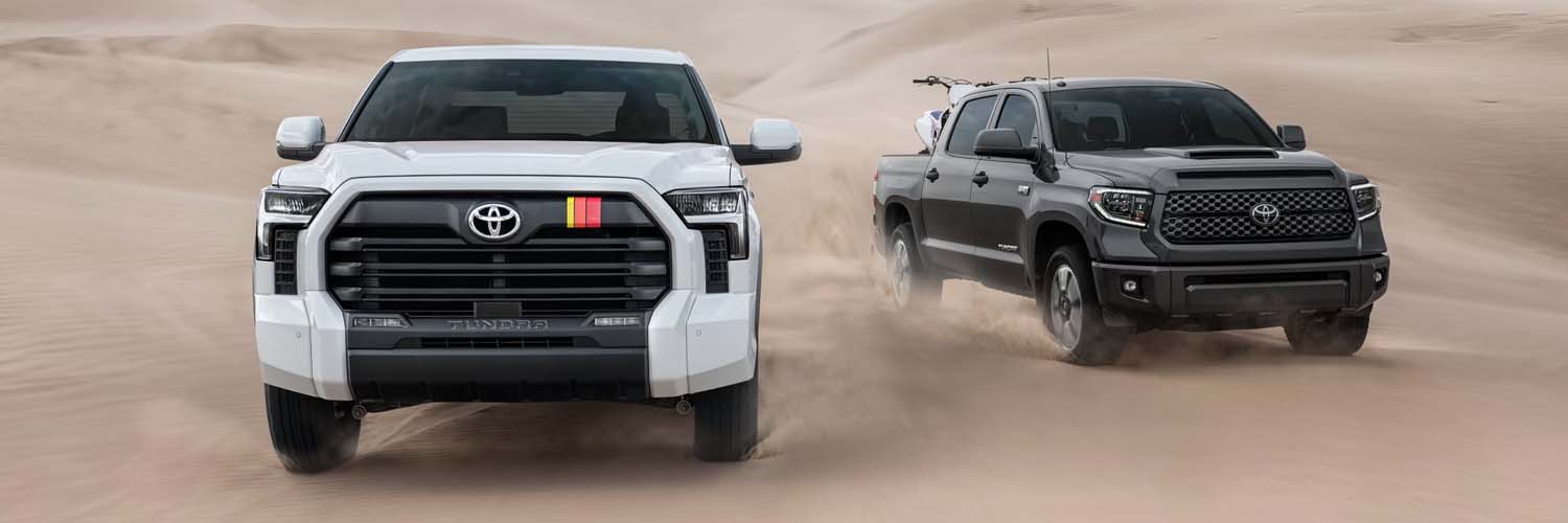 Front driver-side view of 2024 Toyota Tundra towing a small boat down the highway with mountains in the background.