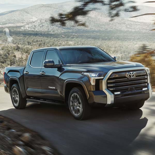 Black 2025 Toyota Tundra driving on mountain highway.