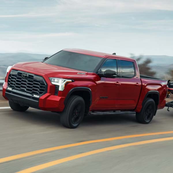 Red 2025 Toyota Tundra driving on mountian highway.