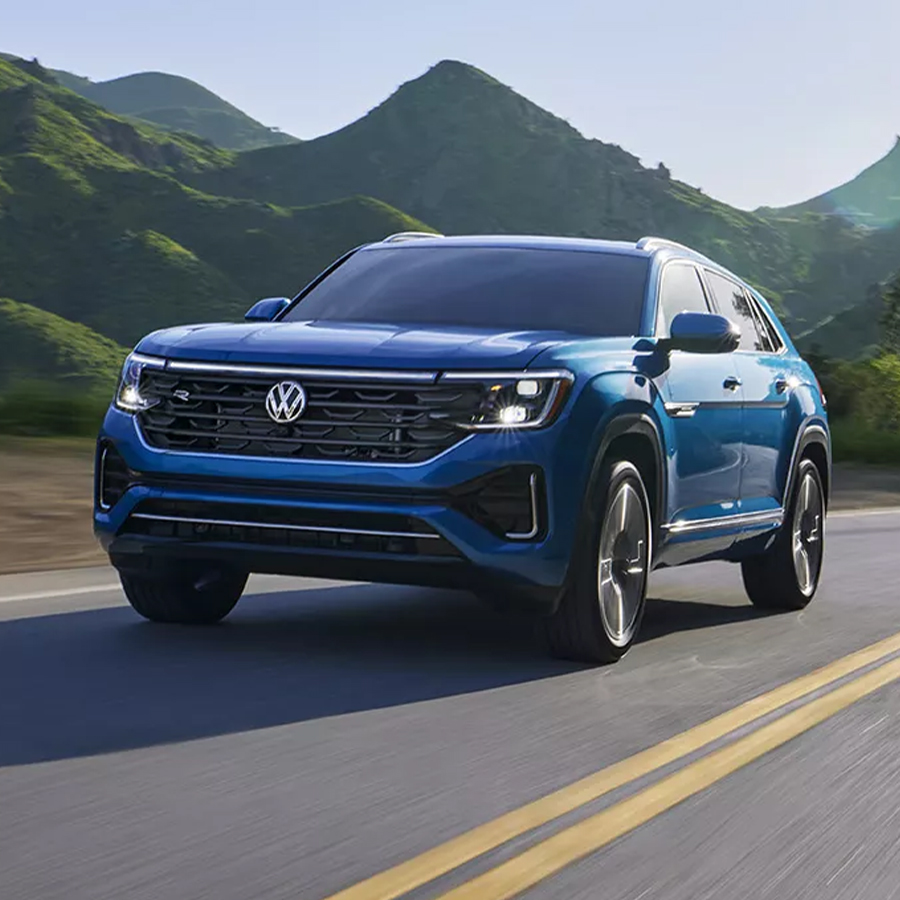 Front 3/4 shot of the 2025 Volkswagen Atlas Cross Sport driving down winding road