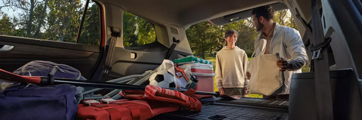 A father and son load sports equipment into the cargo area of an Atlas.