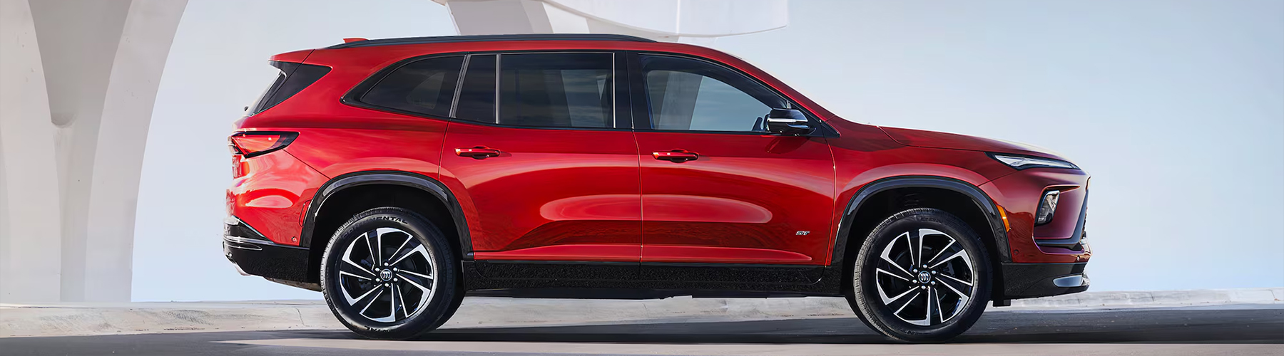 Side View of a Red 2025 Buick Enclave ST Under a Bridge.