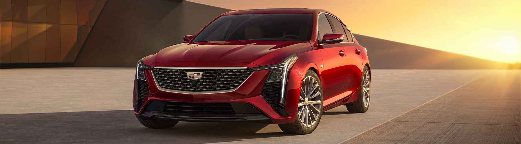 Front Driver's Side View of Parked Red 2026 Cadillac CT5 With Beautiful Sun Setting Displayed