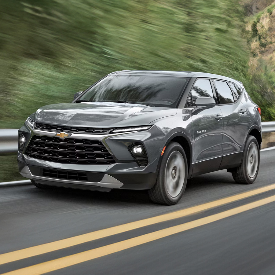 2026 Chevy Blazer driving down a road with trees in the background