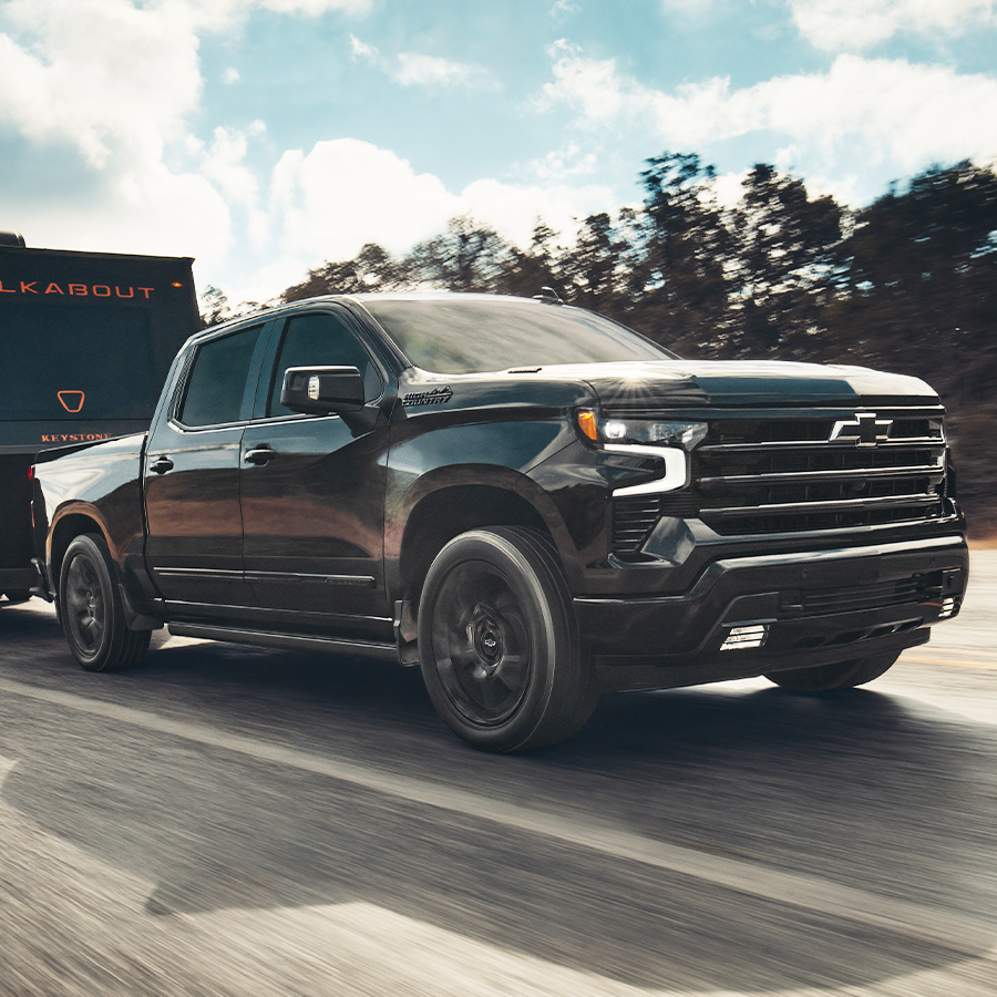 2026 Chevy Silverado 1500 Crew Cab High Country going down the highway hauling an RV.