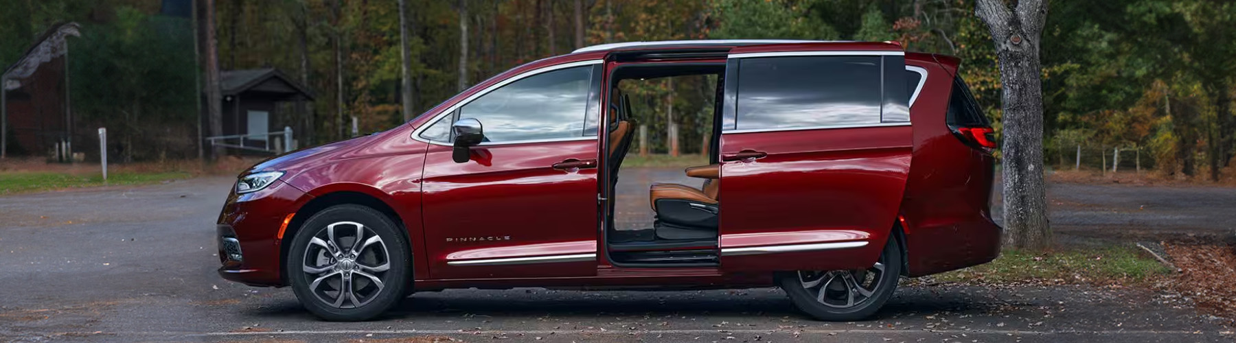 Side view of the 2026 Chrysler Pacifica at a wooded park with the door open