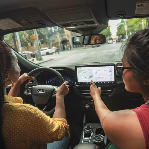 Two women inside a 2026 Ford Escape, while the passenger is looking at the navigation on the center screen