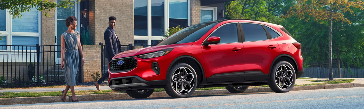 Two people walking up to a 2026 Ford Escape® SUV parked on a city street