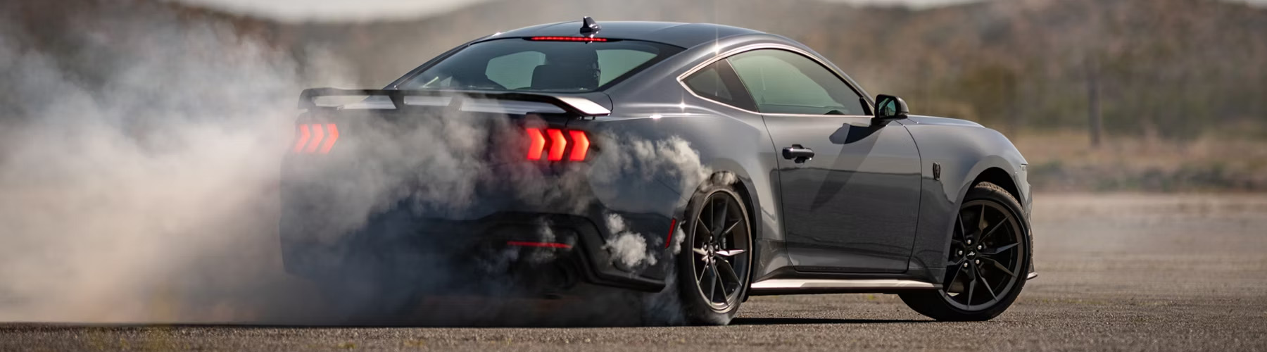2026 Ford Mustang Dark Horse® Fastback in Vapor Blue Metallic with a driver performing burnouts on a closed course