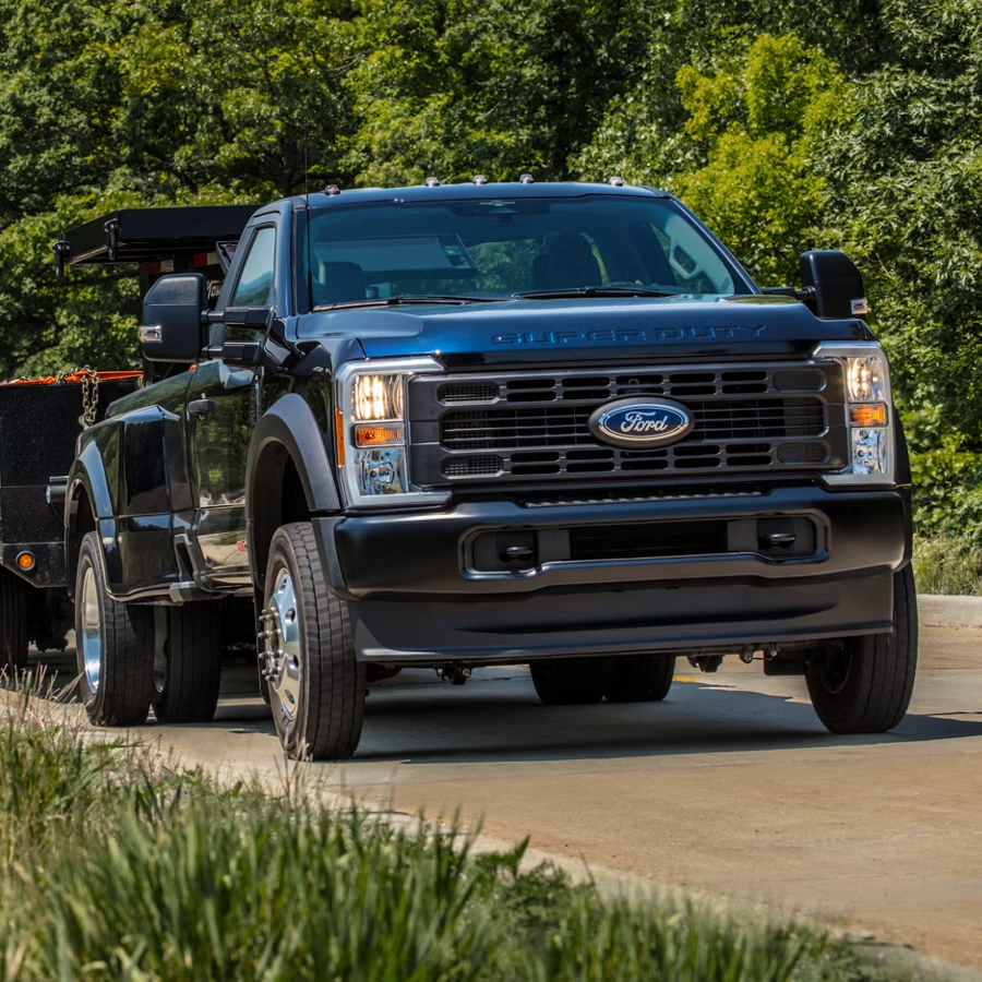 2026 Ford Super Duty® pickup pulling a large flat bed trailer up a paved hill