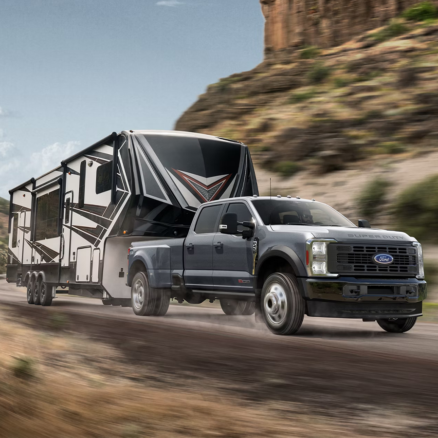 2025 Ford Super Duty® F-450® XL in Carbonized Gray pulling a camper down a winding road