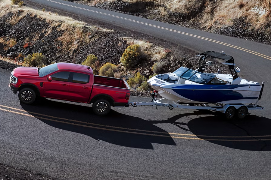 A 2026 Ford Ranger® truck pulling a speed boat on a winding, mountainous highway