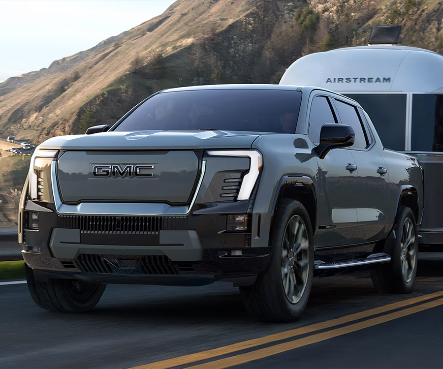 The Sierra EV Pickup Truck Towing a Trailer with Mountains in the Background