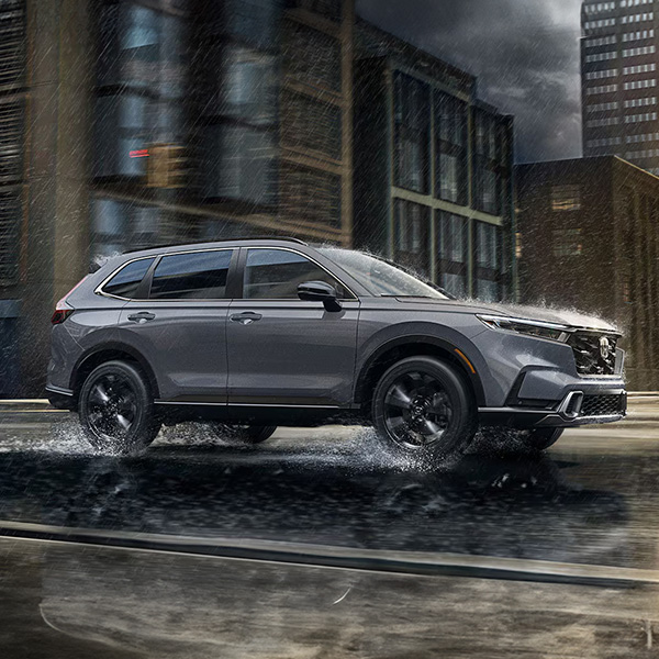Exterior shot of a 2026 Honda CR-V driving on a highway during a rainstorm.