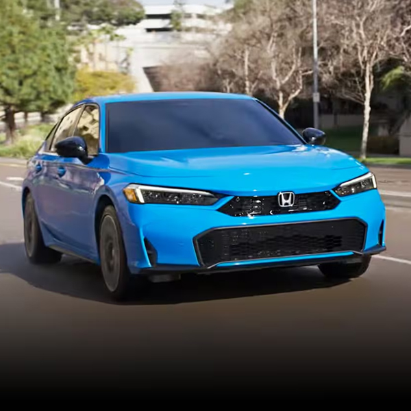 2026 Honda Civic Hatchback Sport Touring Hybrid in Boost Blue Pearl driving on an urban road
