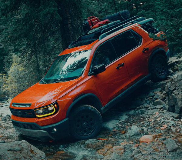 2026 Honda Passport in Sunset Orange descending rocky terrain.