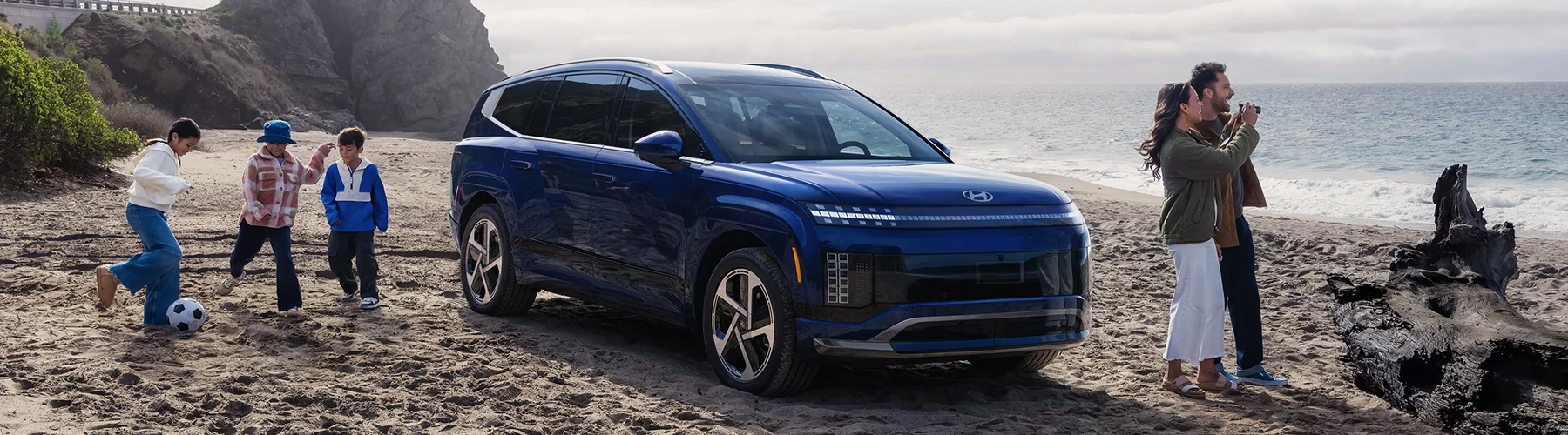 A family pictured with a 2026 IONIQ 9 on beach.