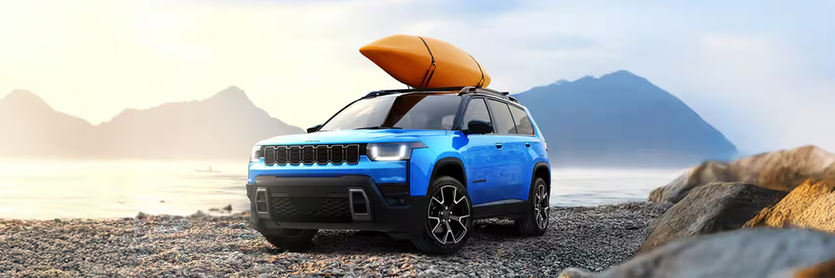 The 2026 Jeep Grand Cherokee parked by the water with a canoe on the roof
