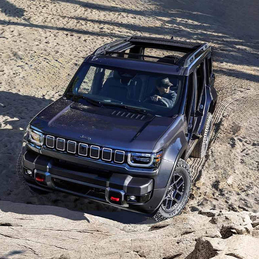 2026 Jeep Recon with its doors and top removed, about to scale a rocky hill off-road.