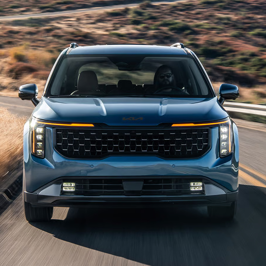 2026 Kia Carnival MPV minivan in blue, front view, revealing a high ground clearance