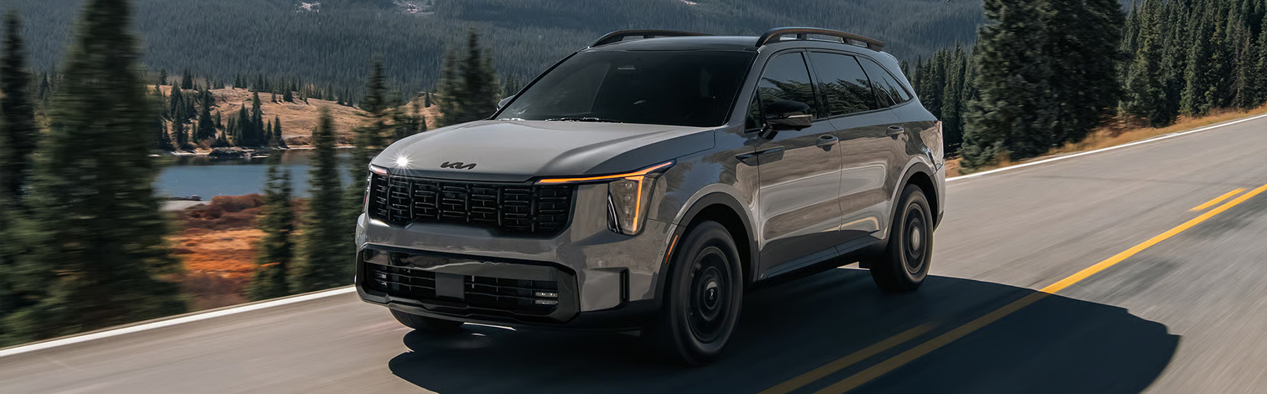 2026 Kia Sorento, three-quarter driver's side view, driving on a road by the lake in the mountains