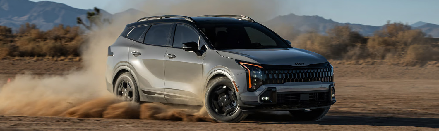 Grey 2026 Kia Sportage driving offroad in a desert