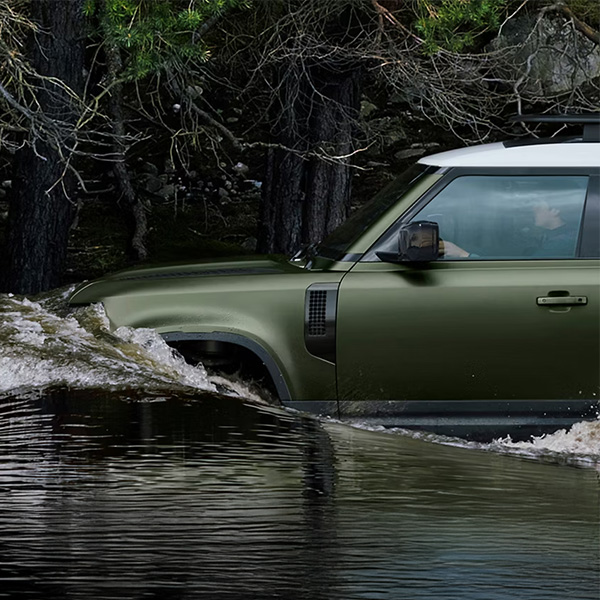 Side view of the 2026 Defender 130 driving through water