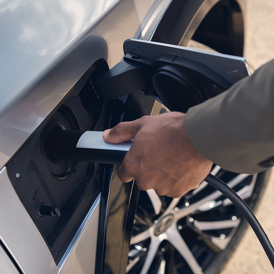 A person plugs a charger into their vehicle's charging port.