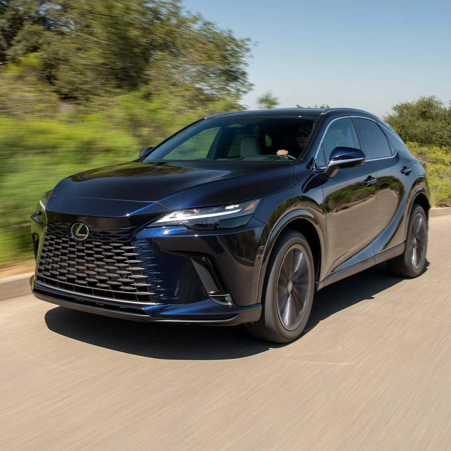 2026 Lexus RX 350 Premium driving on a scenic road, showcasing bold front grille and LED headlights