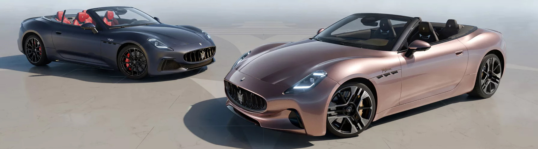 Two 2026 Maserati GranCabrio convertibles parked side-by-side, one in dark blue with a red interior and one in rose gold with a black interior.