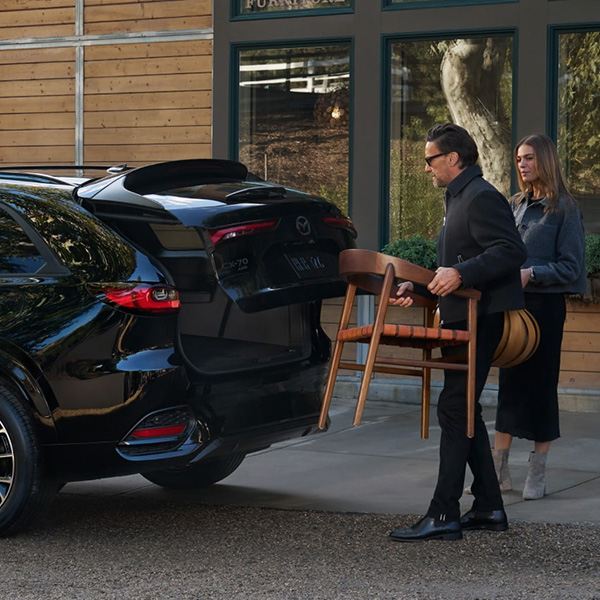 Rear view of a Mazda CX-70 with the liftgate open as cargo is being loaded.