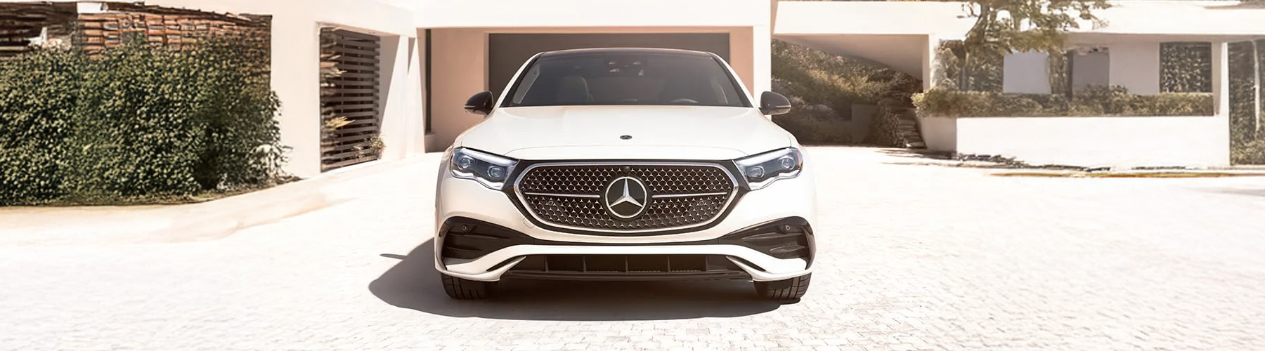 Front view of the 2026 Mercedes-Benz E-Class parked in front of a modern house