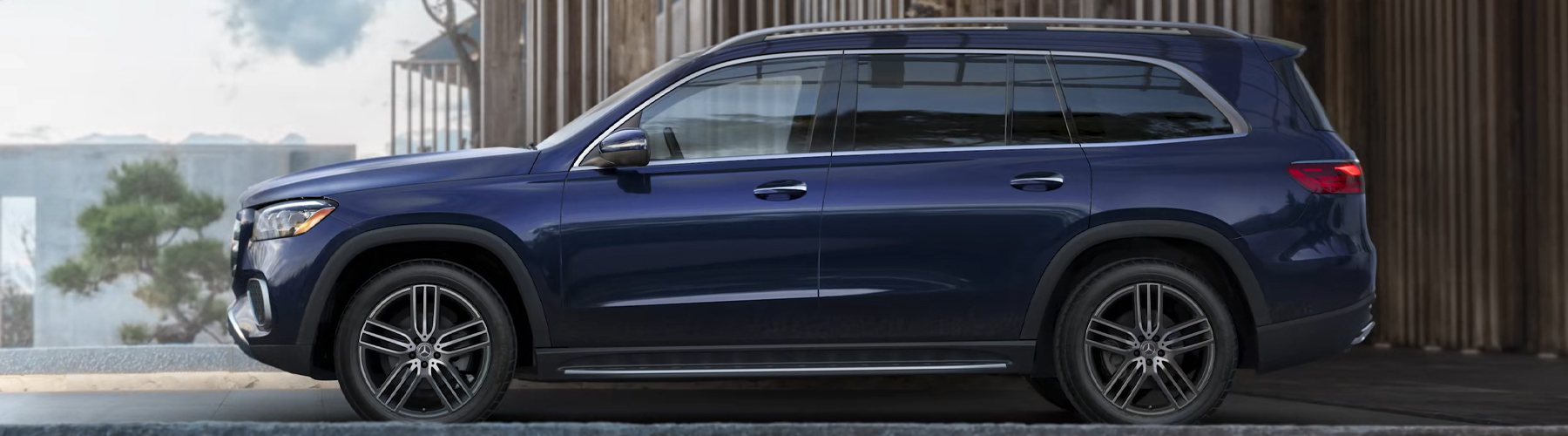 2026 Mercedes-Benz GLS in deep blue shown in full side profile near modern architecture