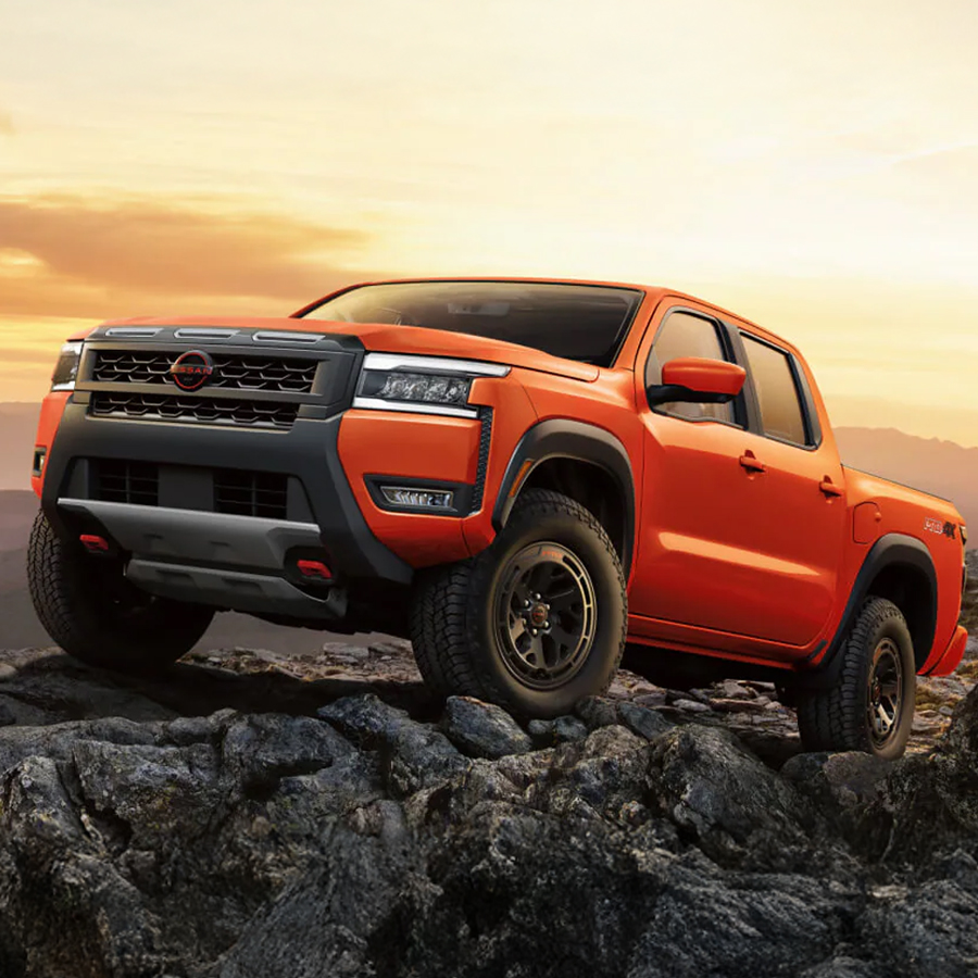 2026 Nissan Frontier in red, parked on a rugged peak with a twilight sky in the background