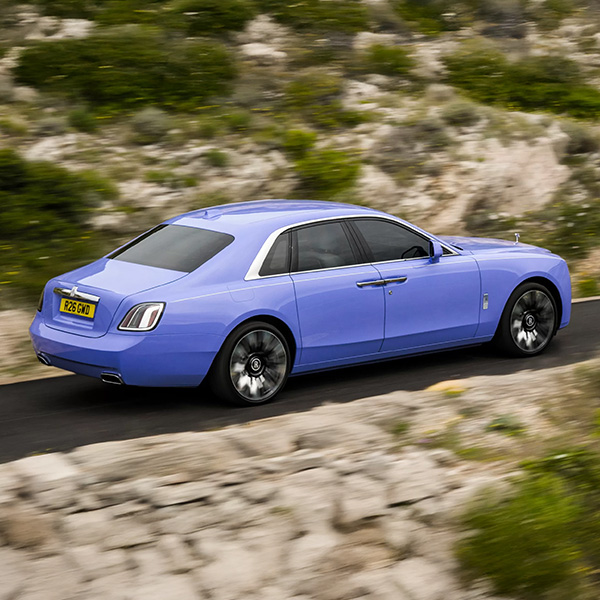 Rear 3/4 shot of the 2026 Rolls-Royce Ghost driving down road
