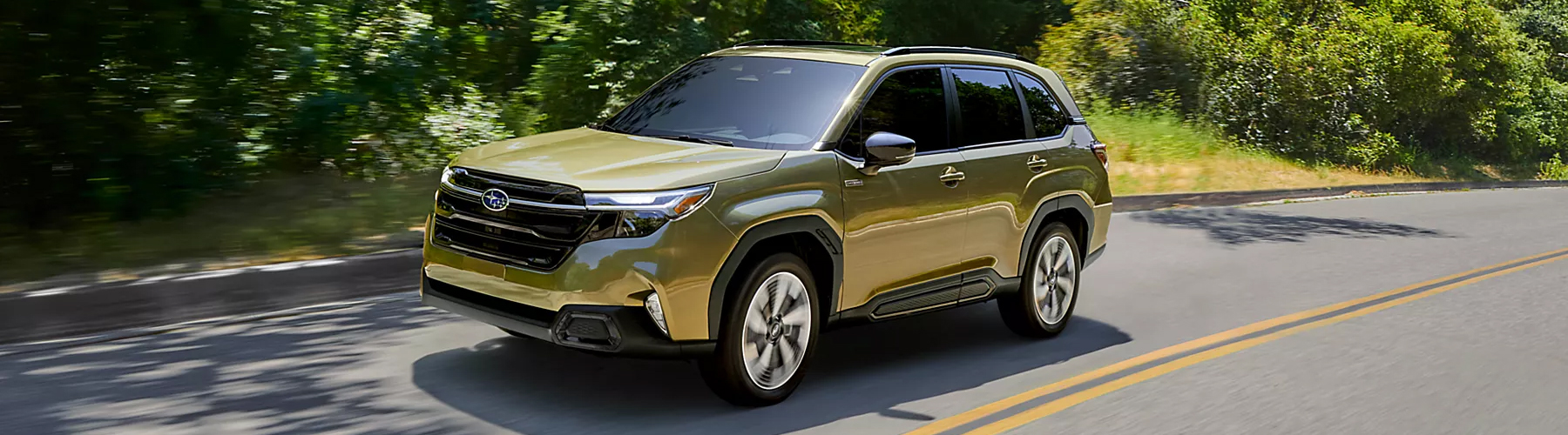 A 2026 Subaru Forester Hybrid AWD SUV driving on a road in a treelined area.