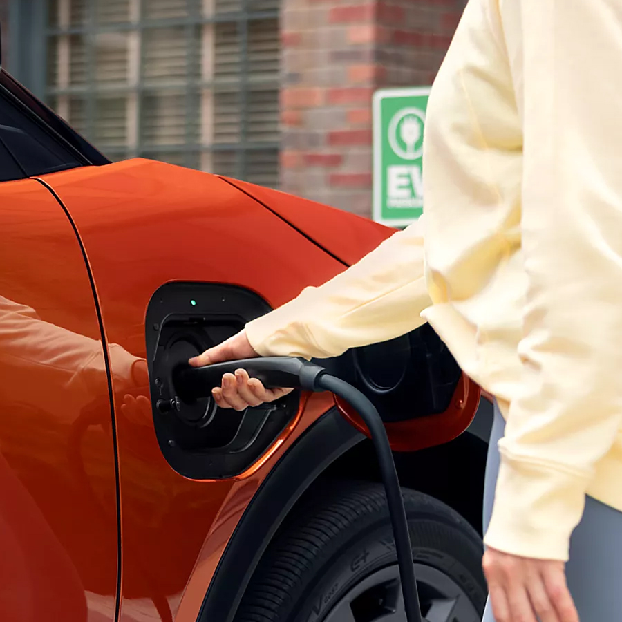 Woman charging her Subaru Uncharted EV SUV at a charging station