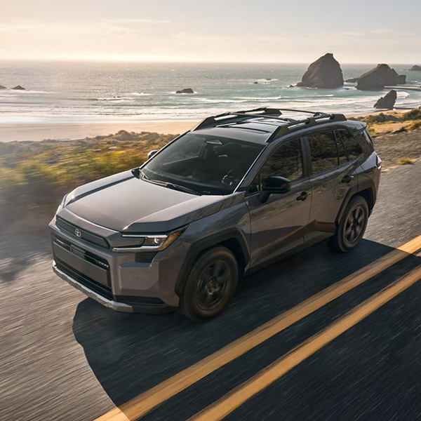 Overhead side shot of the 2026 Toyota RAV4 driving on road by water