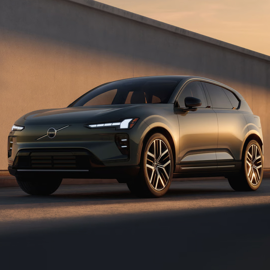 A Volvo EX60 parked beside a wall, viewed from a front three-quarter angle in soft sunlight.