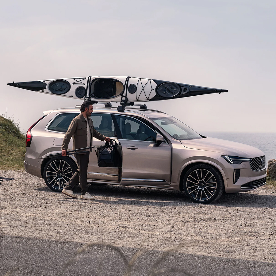The Volvo XC90 with a kayak holder and a man packing bags into the passenger seat