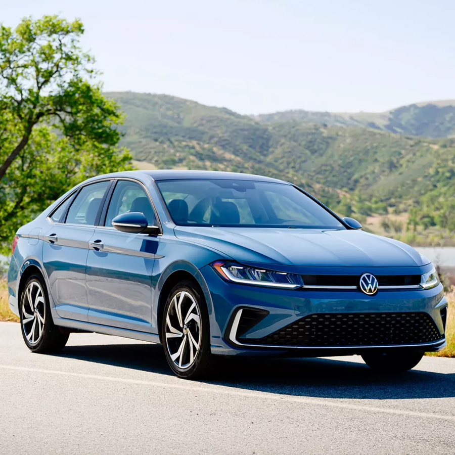 Front view of a Jetta shown in Monterey Blue Pearl parked with wooded hills in the background