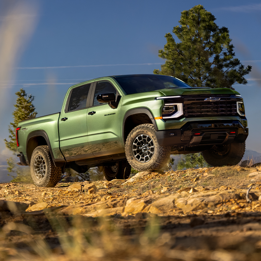 A Green 2027 Chevy Silverado 1500 Off-roading on a Rugged, Rocky Hill