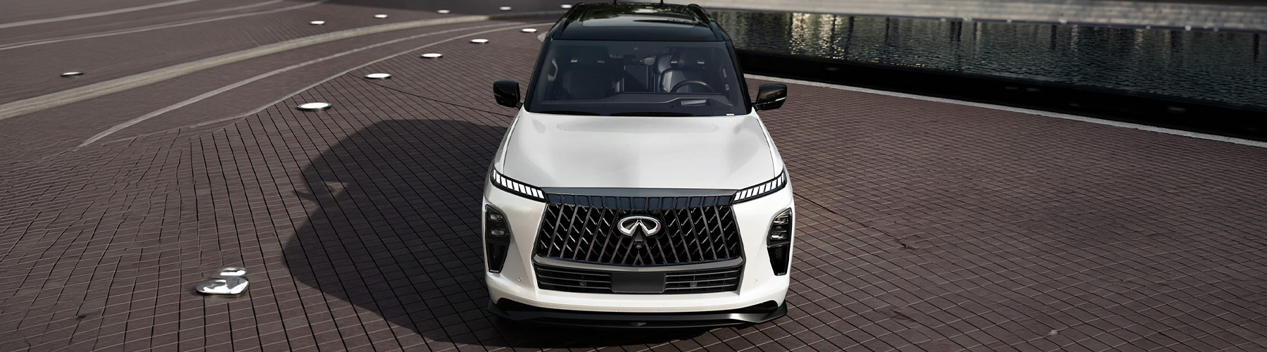 An exterior front view of a parked 2027 INFINITI QX80 shown in white exterior color