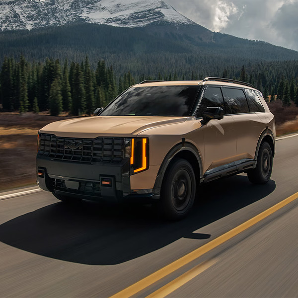 2027 Kia Telluride driving down a road by a mountain