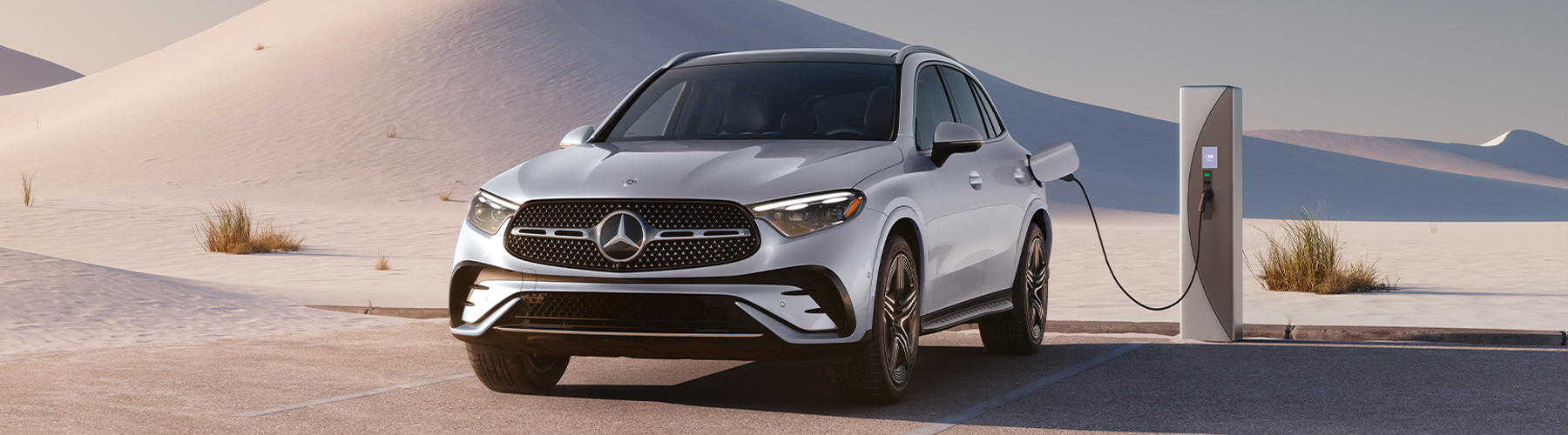 2027 Mercedes-Benz GLC electric SUV charging at an outdoor charging station in a scenic desert setting