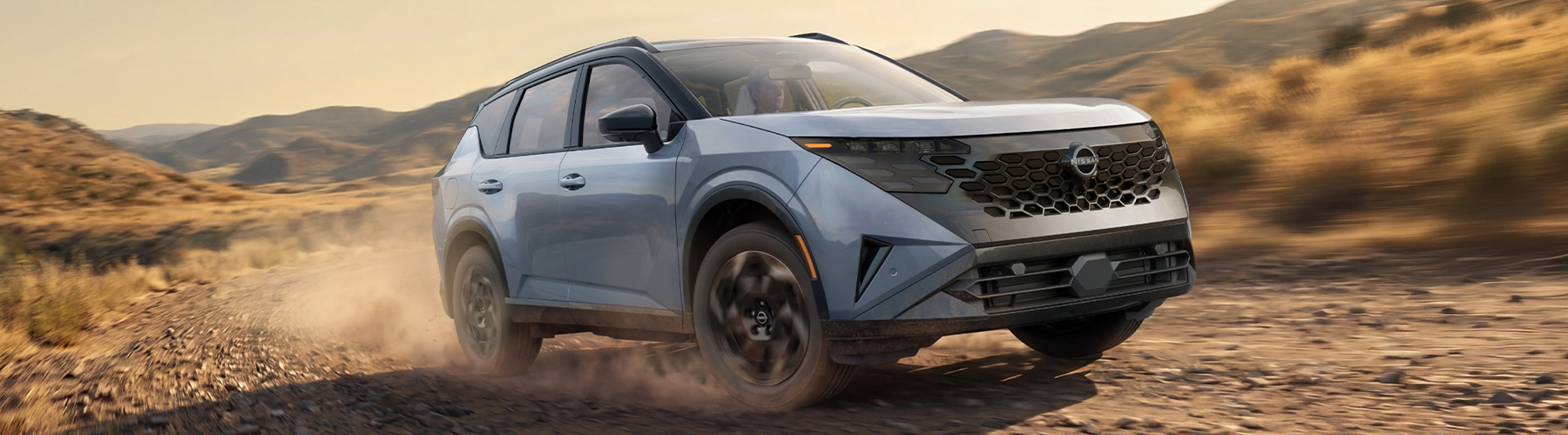 2027 Nissan Rogue Hybrid driving on dirt road