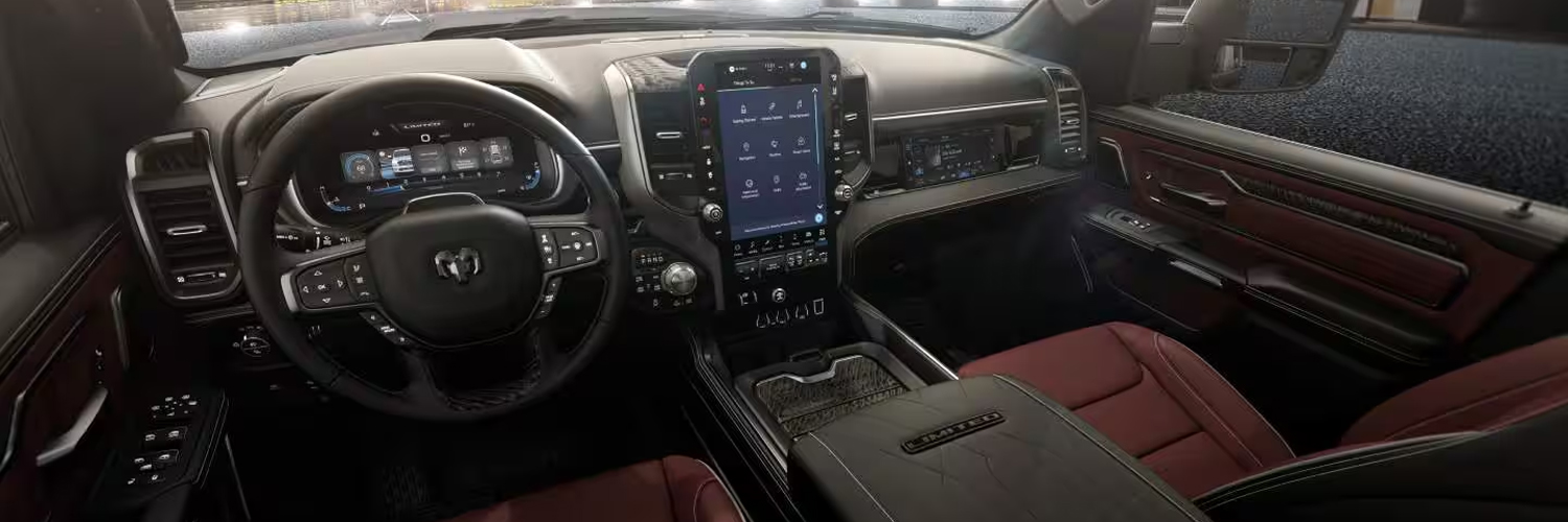 Display The front row of a 2027 Ram 1500 Limited 4x4 Crew Cab with red bucket seats, a Digital Cluster Display and large Uconnect touchscreen.