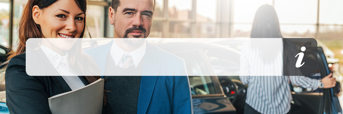 Portrait of two happy car sales consultants working inside vehicle showroom.