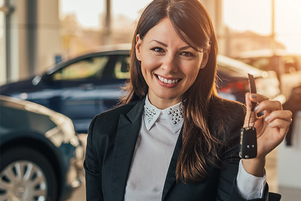 Cheerful young woman showing her new car key at Mac Haik Dodge Chrysler Jeep Ramship.