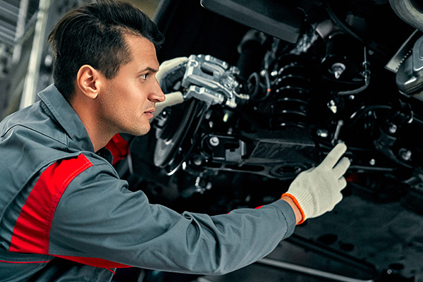 Mechanic in uniform is working in auto service. Car repair and maintenance.